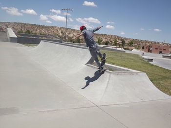 Full length of man skateboarding at skateboard park against sky