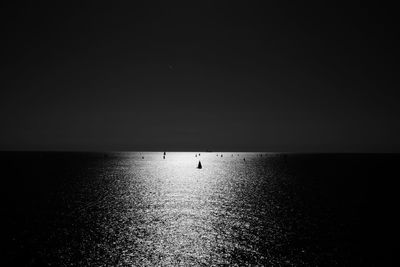 Silhouette of sailing boats in ocean against sky