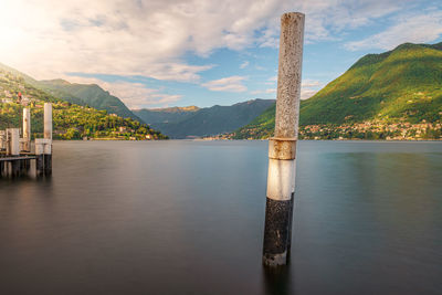 Wooden posts in lake against sky