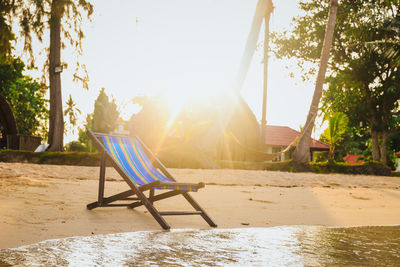 Chairs and tables on beach against sky on sunny day