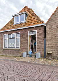 Man with granddaughter standing outside house