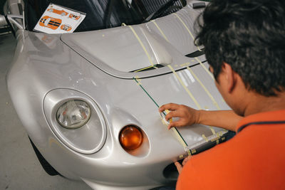 Rear view of mechanic applying adhesive tape on car
