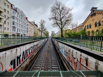 View of railroad tracks coming out of tunnel along buildings