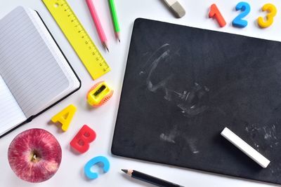 High angle view of school supplies with apple on table