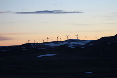 Silhouette windmills on mountain at sunset
