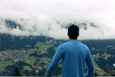 Rear view of man standing on mountain against sky