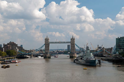 View of suspension bridge over river against cloudy sky