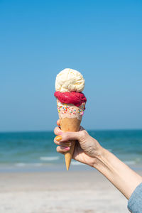 Cropped hand of woman holding ice cream at beach