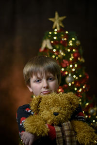 Portrait of boy with christmas tree at night