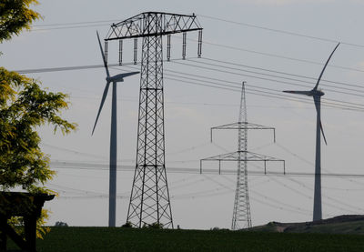 Low angle view of electricity pylon on field against sky