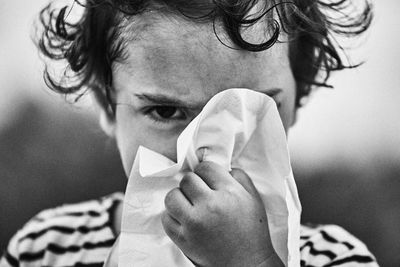 Close-up portrait of boy cleaning nose