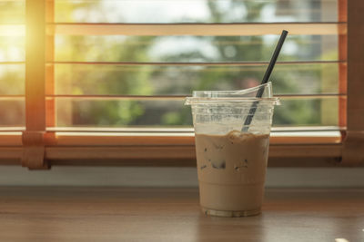 Iced coffee in a plastic cup set by the window