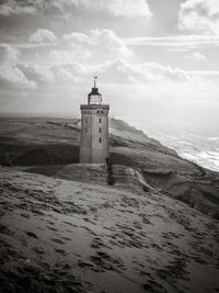 Lighthouse amidst sea and buildings against sky