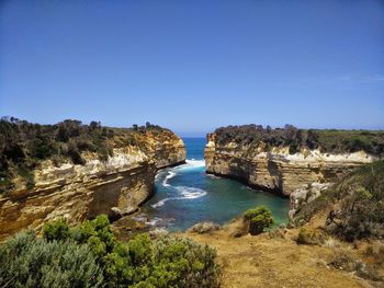 Scenic view of cliff and sea against clear blue sky