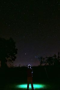 People standing on field against sky at night