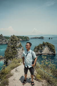 Rear view of man standing at beach against sky