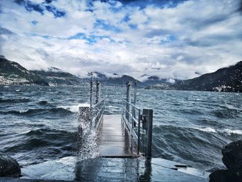 Wooden posts in sea against sky