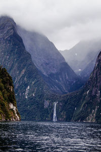 Scenic view of sea by mountains against sky