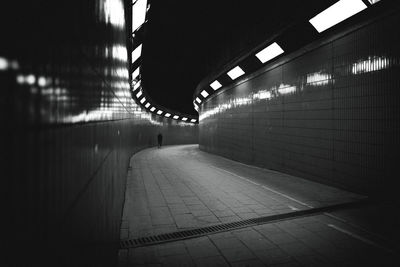 Rear view of man walking in illuminated tunnel