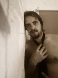 Portrait of young man standing against wall at home
