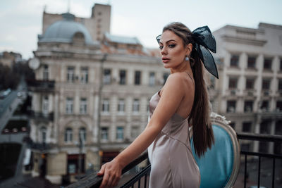 Portrait of woman standing against railing in city