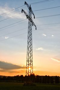 Low angle view of silhouette electricity pylon on field against sky