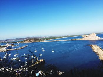 Scenic view of sea by city against clear blue sky