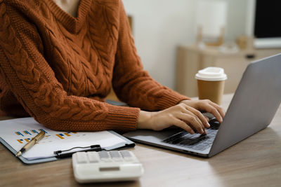 Midsection of woman using laptop on table