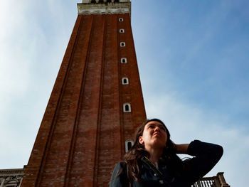 Low angle view of woman against tower in city