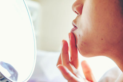 Cropped image of mid adult woman looking at pimples in mirror