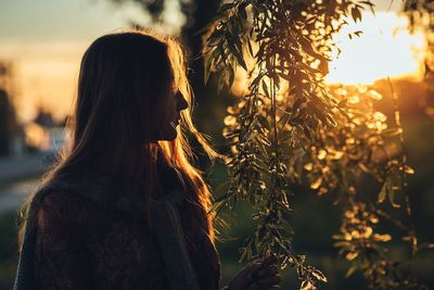 Woman standing by plants during sunset