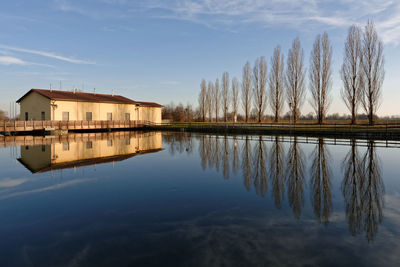 Reflection of house on lake by building against sky