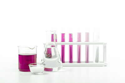 Close-up of pink bottles on table against white background
