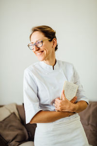 Female chef in uniform holding notebook and smiling