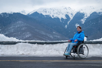 Rear view of man riding bicycle on snowcapped mountain