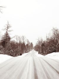 Road amidst snow covered trees against sky