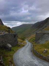 Road leading towards mountains against sky