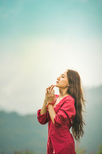 Young woman wearing hat standing against sky