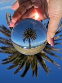 Midsection of person holding umbrella against sky