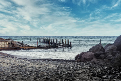 Wooden posts on beach against sky