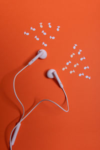 High angle view of headphones on table against orange background