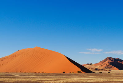 Scenic view of desert against clear blue sky