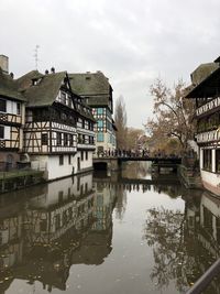 Arch bridge over river by buildings against sky