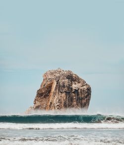 Rock formation on beach against clear sky