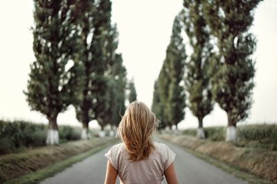 Rear view of woman on road against clear sky