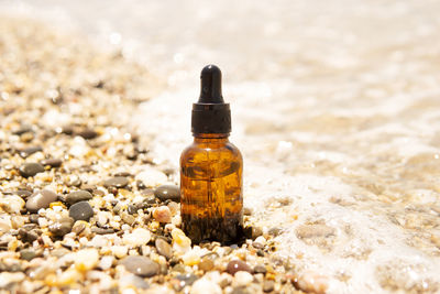 Cosmetic serum in a glass bottle with a pipette on stones