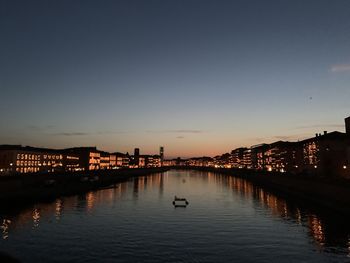 Illuminated bridge over river against clear sky at sunset