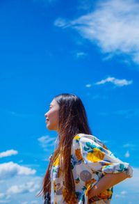 Low angle view of woman against clear blue sky