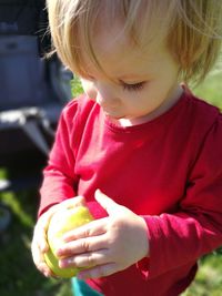 Close-up of baby girl having lemon while standing on field