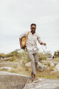 Young man walking on rock against sky during picnic